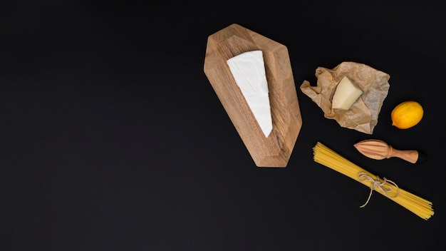 Free photo uncooked italian pasta ingredient with wooden juicer on kitchen table