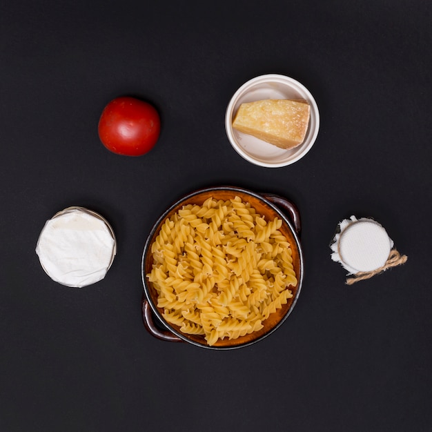 Free photo uncooked italian twisted fusilli pasta and ingredient over kitchen counter