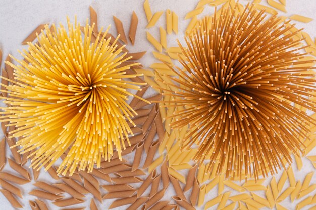 Uncooked macaroni with fresh raw pasta on white space. 