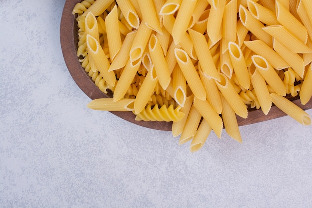 Free photo uncooked macaroni on wooden bowl