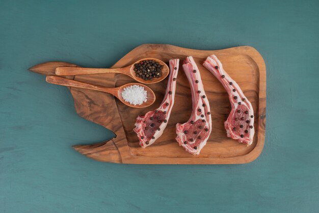 Кусочки сырого мяса на деревянной доске со специями.