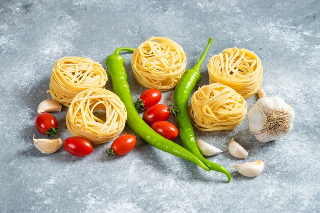 大理石の背景に野菜と未調理の巣スパゲッティ