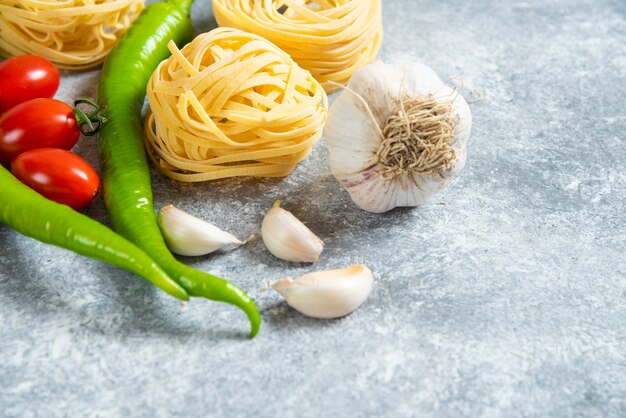 大理石の背景に野菜と未調理の巣スパゲッティ