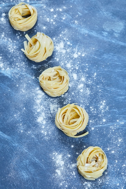 Uncooked nests of tagliatelle pasta isolated.