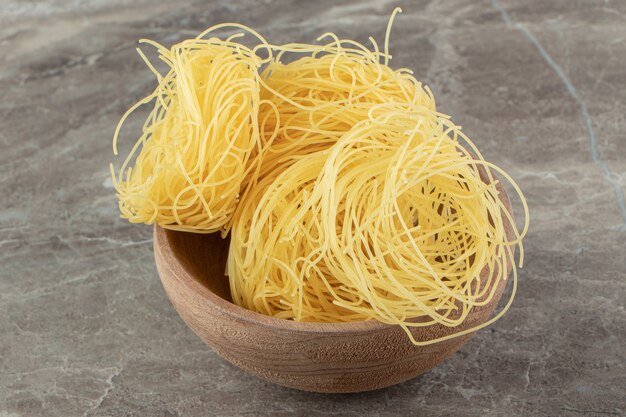 Uncooked noodle nests in wooden bowl