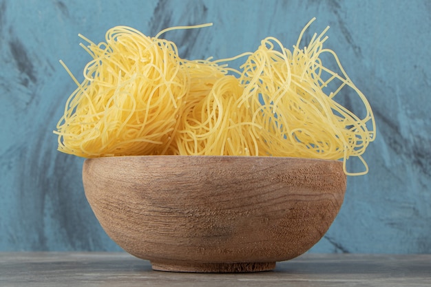 Uncooked noodle nests in wooden bowl