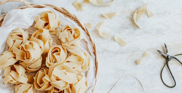 Uncooked pappardelle pasta on a wooden basket