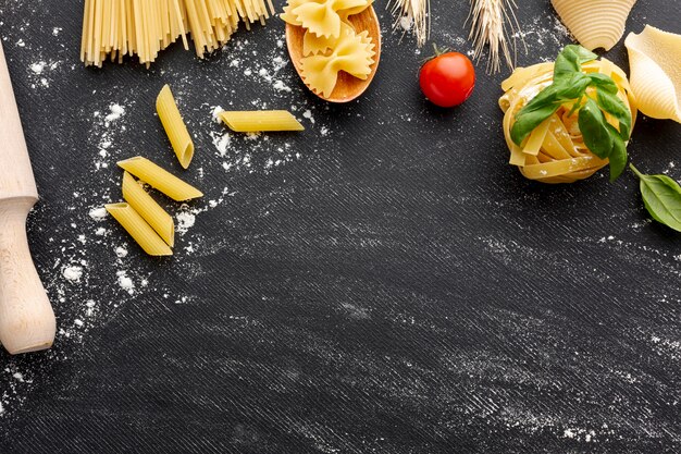 Uncooked pasta arrangement frame on black background with copy space