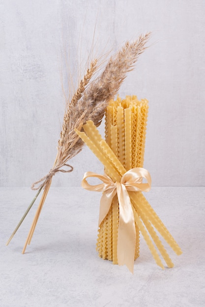 Free photo uncooked pasta tied with ribbon on white surface