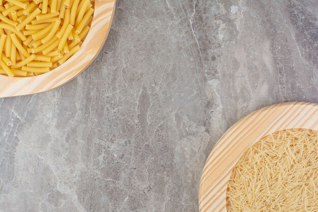 Uncooked pastas in a wooden platter on the marble. 