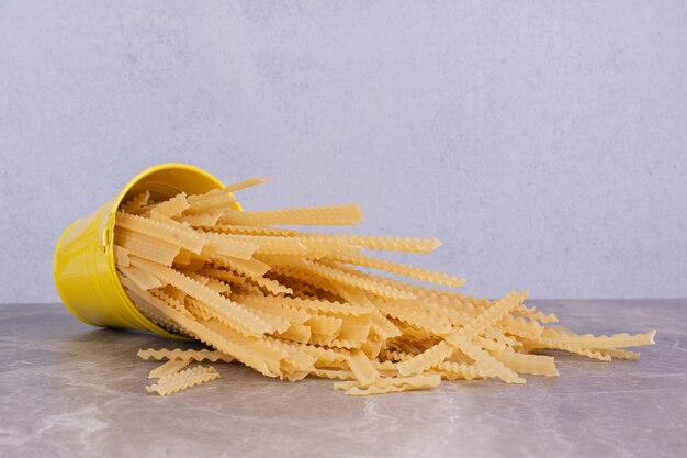 Free photo uncooked pastas in a yellow metallic container bucket