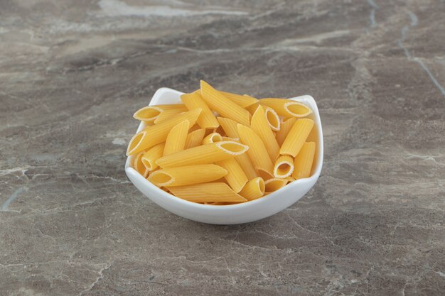 白いボウルに未調理のペンネパスタ