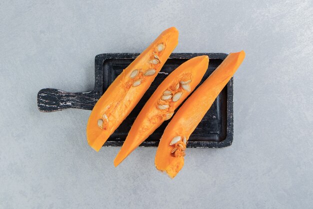 Uncooked pumpkin on the board , on the marble background.