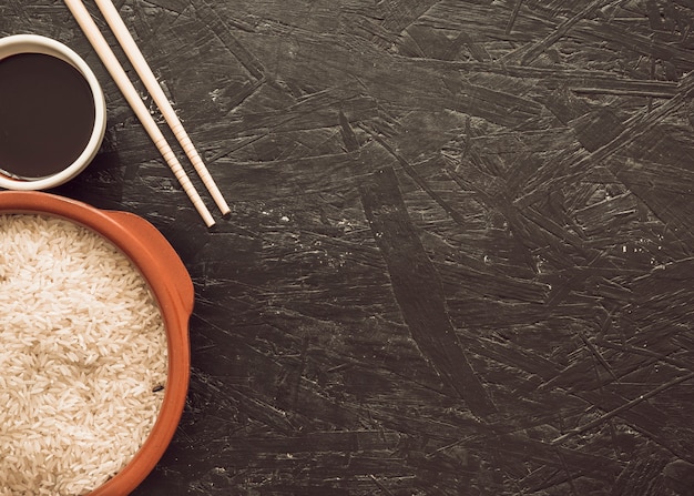 炊飯米の穀物、醤油のボウルと箸のテクスチャ付きの背景