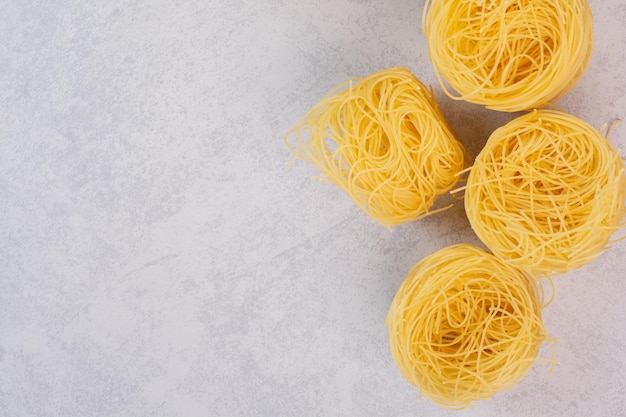 Uncooked spaghetti nests on marble table.