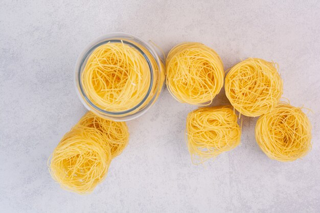 Uncooked spaghetti nests on stone surface with glass jar