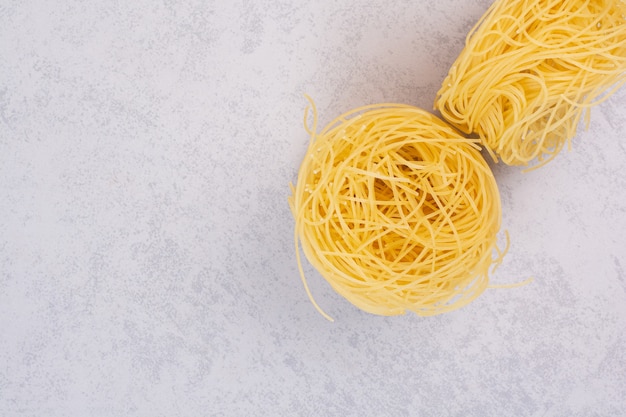 Foto gratuita nidi di spaghetti crudi sulla superficie della pietra