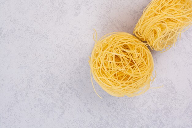 Uncooked spaghetti nests on stone surface