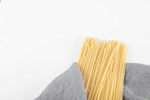 Uncooked spaghetti pasta on gray tablecloth.