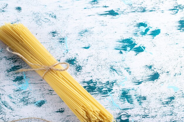 요리하지 않은 스파게티 파스타는 다채로운 표면에 밧줄로 묶여 있습니다. 고품질 사진