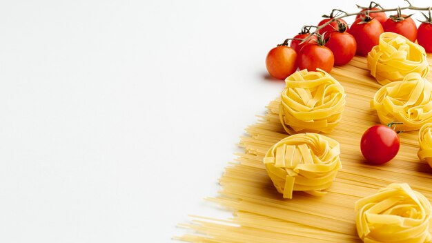 Uncooked spaghetti tagliatelle and tomatoes with copy space