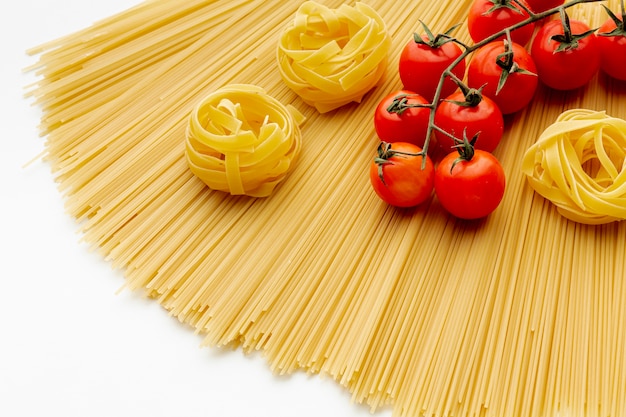 Сырые спагетти тальятелле и помидоры