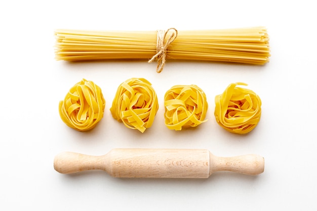 Uncooked spaghetti and tagliatelle with rolling pin