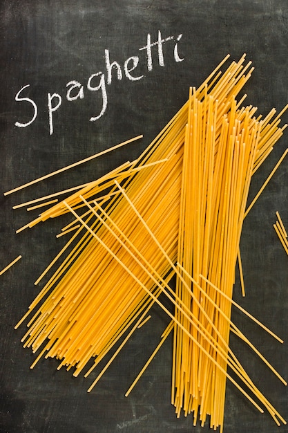 Uncooked spaghetti and text written on blackboard
