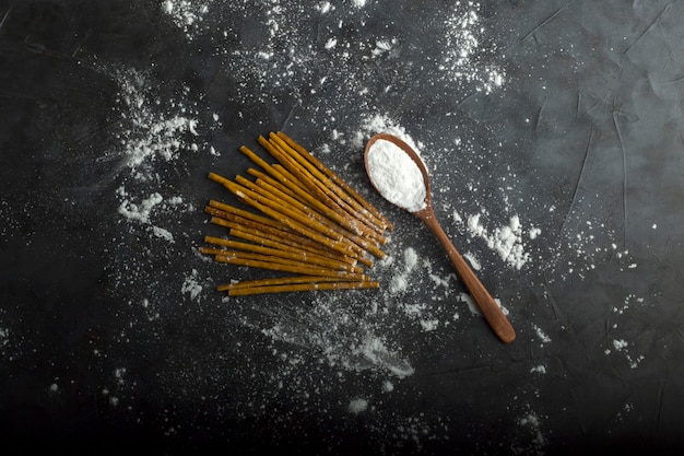 Spaghetti crudi con farina in un cucchiaio di legno