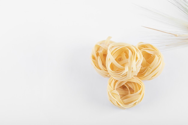 Uncooked tagliatelle nests on white background. High quality photo