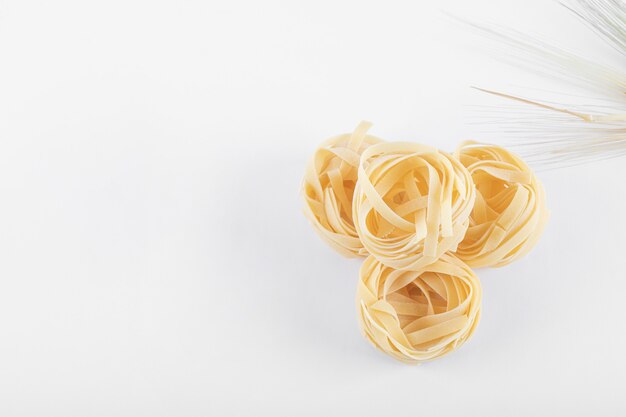 Uncooked tagliatelle nests on white background. High quality photo