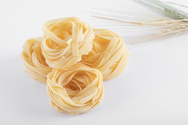 Uncooked tagliatelle nests on white.