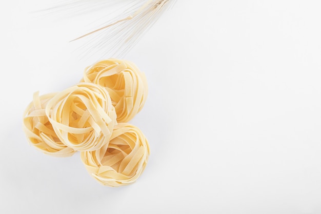 Free photo uncooked tagliatelle nests on white.