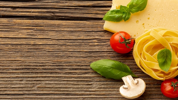 Uncooked tagliatelle with basil leaves hard cheese tomatoes and copy space