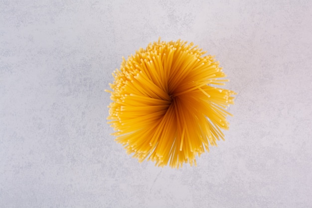 Uncooked yellow spaghetti pasta on stone surface