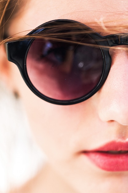 Une jolie fille avec des lunettes de soleil rondes
