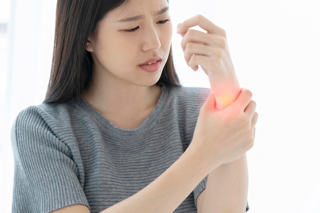 Unhappy asian woman hand touch wrist with hand hurt from work or exercise white background