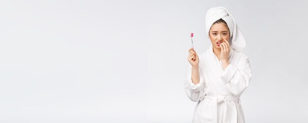 Несчастная красивая женщина чистит зубы на белом фоне