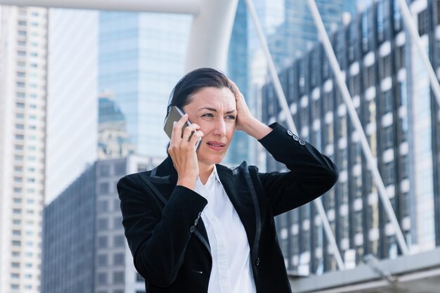 Несчастная деловая женщина разговаривает по мобильному телефону в городе