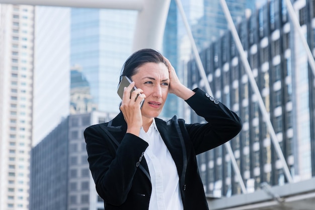Unhappy businesswoman talking on mobile phone in city