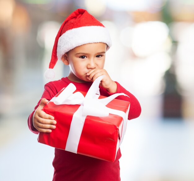 Unhappy child holding a present with blurred background