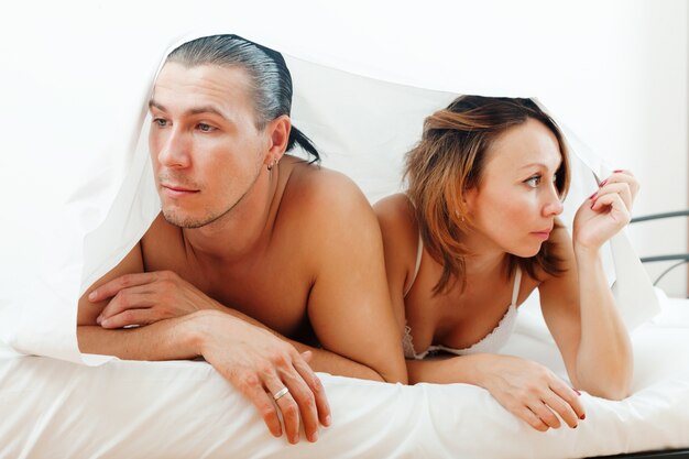 Unhappy couple under sheet