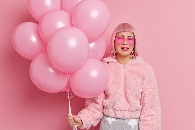 Free photo unhappy desperate woman cries as none come on her party feels lonely and upset holds bunch of inflated balloons