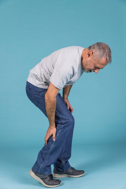 青い壁紙に激しい痛みに苦しんでいる不幸な男 プレミアム写真