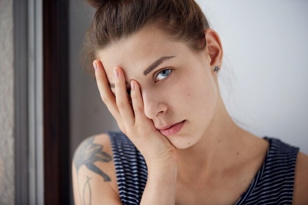 Unhappy overwhelmed girl having headache bad day keeps hands on face