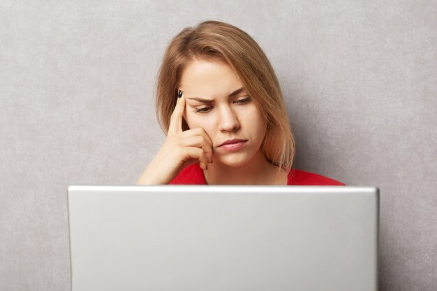 Unhappy pensive serious female copywriter concentrated on writing new article