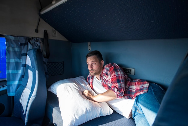 Unhappy truck driver waking up in his vehicle cabin feeling lost, tired and depressed of his way of life