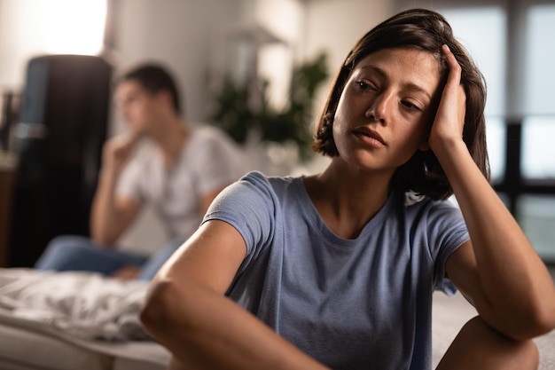 Foto gratuita donna infelice che contempla dopo una discussione con il suo ragazzo a casa l'uomo è sullo sfondo