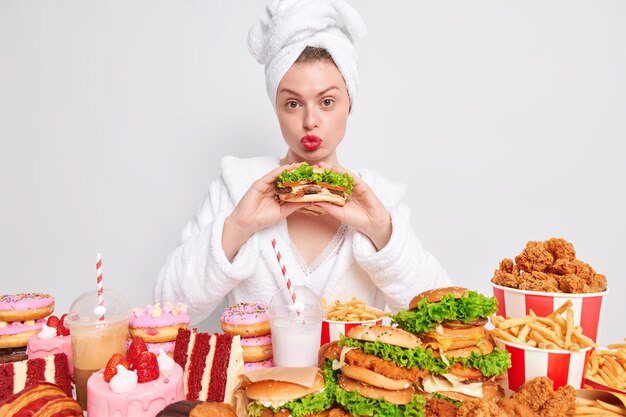 不健康な栄養減量ダイエットとごみ遣いの概念。素敵な主婦が唇を丸く保ち、おいしい食欲をそそるサンドイッチを食べる