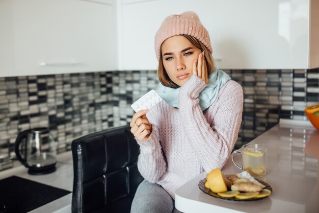 Unhealthy young woman holding pill at hands while have a flu